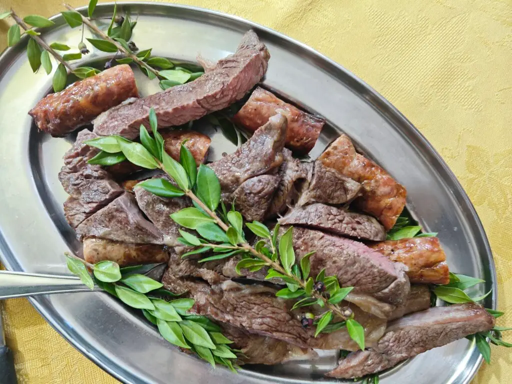 Ein Teller voll mit Steak, Salsiccia und Kräutern - authentisch essen im sardischen Agriturismo