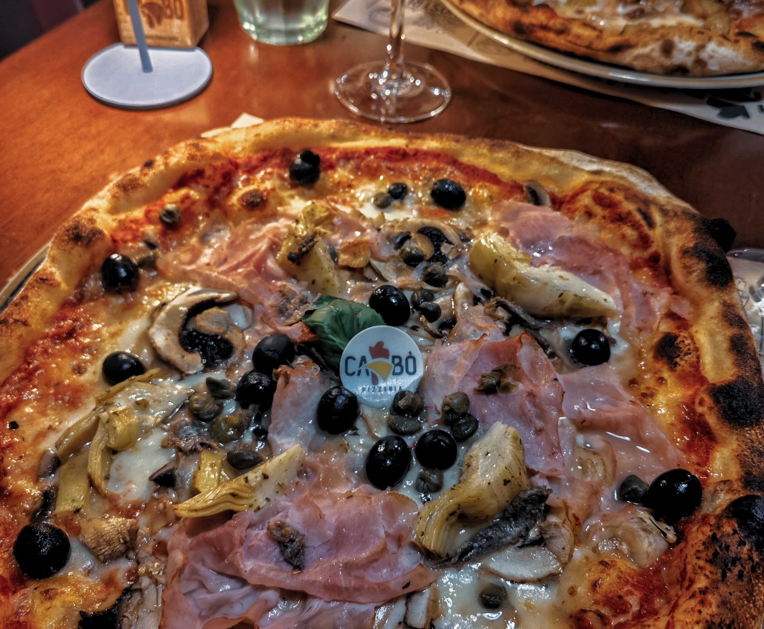 Eine neapolitanische Pizza auf Sardinien, belegt mit Oliven, Schinken, Artischocken und Champignons