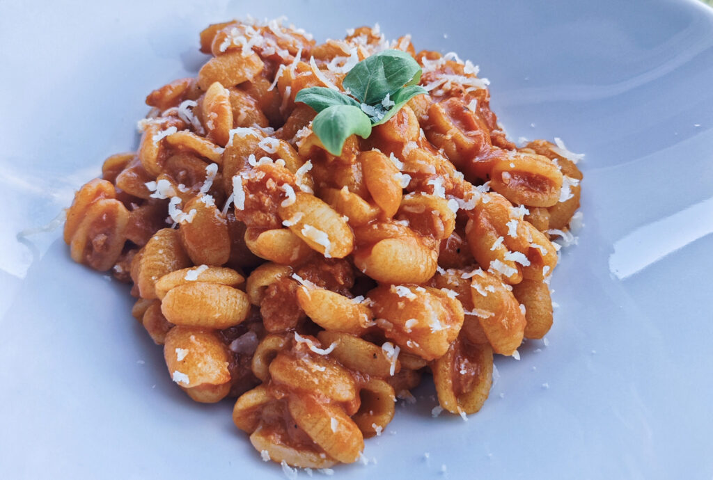 Ein Teller mit der traditionellen Gnocchetti Sardi, Pasta mit Tomatensoße, Salsiccia, und Pecorino