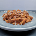 Ein Teller mit traditionellem sardischen Malloreddus alla Campidanese Rezept, geriffelte Pasta mit Tomatensoße, Salsiccia und Pecorino Sardo