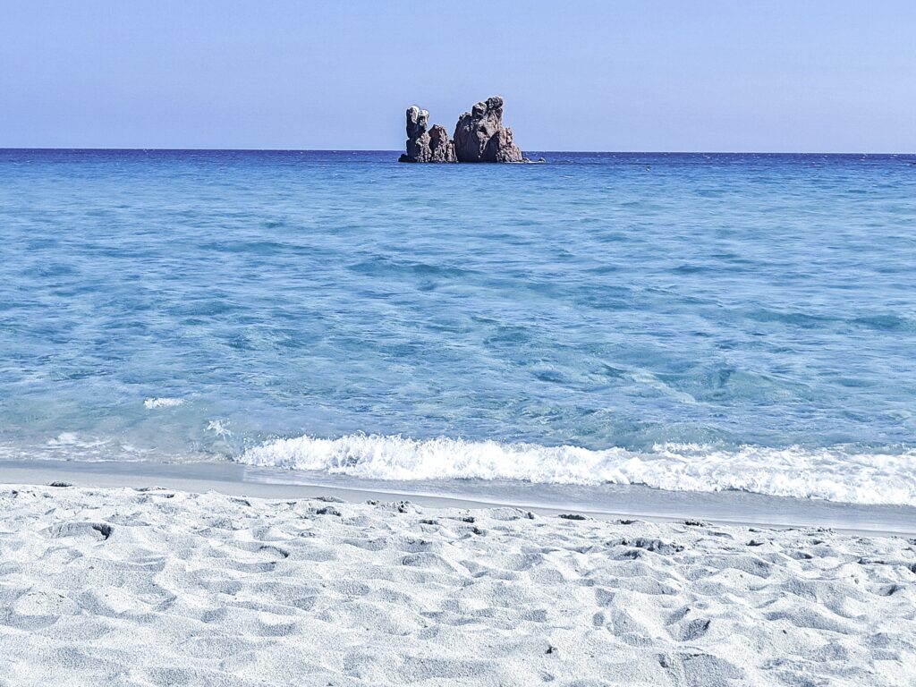 Charakteristischer roter Felsen im glasklaren Wasser des Spiaggia di Cea, einer der ikonischen Strände Sardiniens