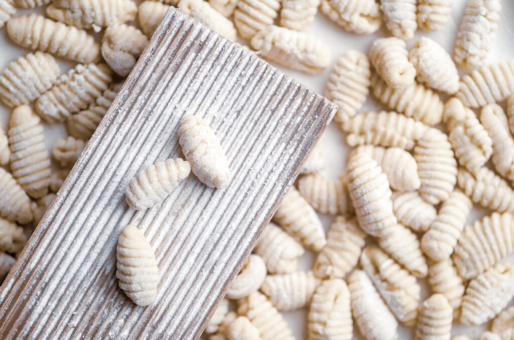 Die traditionelle sardische Pasta Gnocchetti Sardi mit dem klassischen Holzbrett, auf dem sie zur geriffelten Form gerollt werden