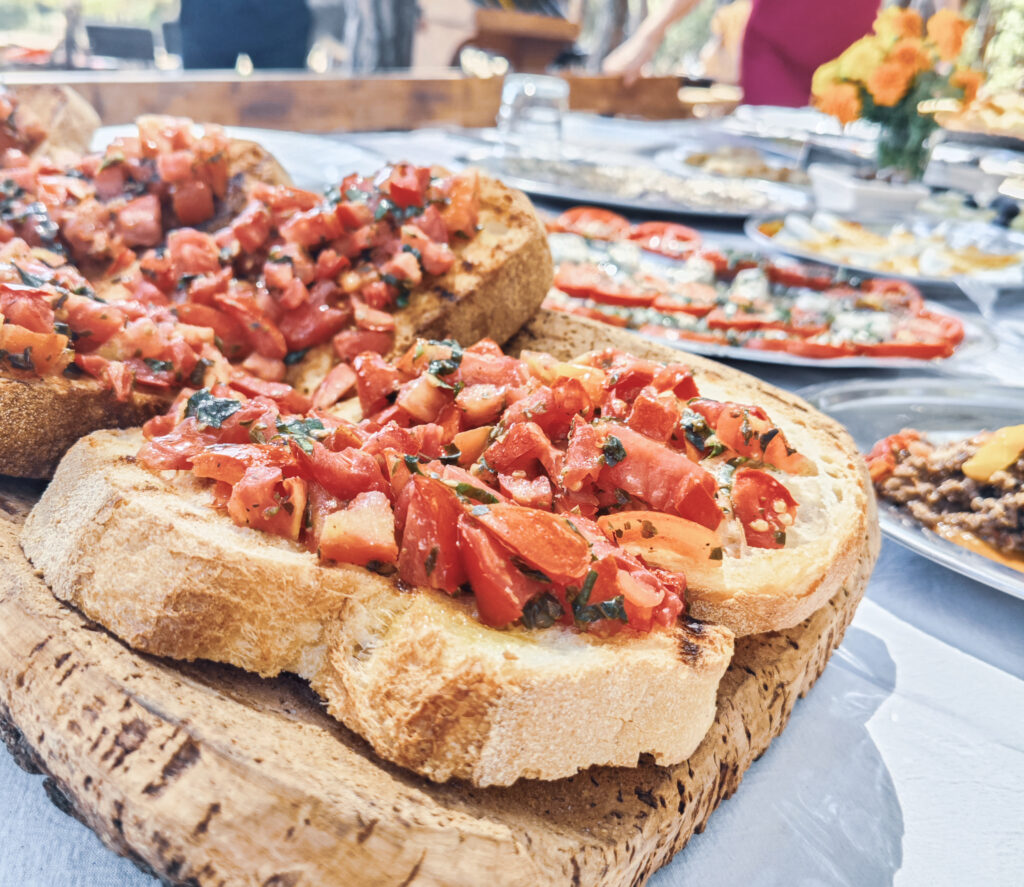 So schmeckt Sardinien im Sommer: Blick auf ein sardisches Picknick mit frischen Tomaten auf sardischem Brot und einem Brett aus Kork