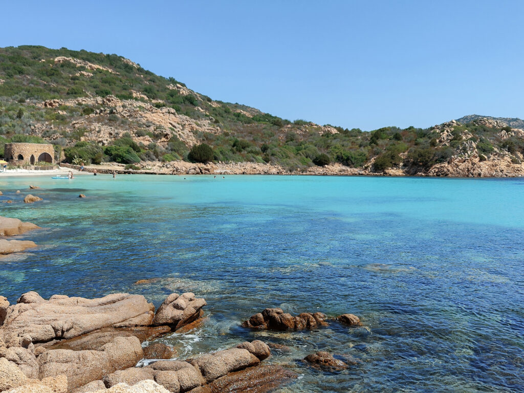 Glasklares Wasser in kleiner Bucht mit historischem Steinbau – abgelegener Strand auf Sardinien
