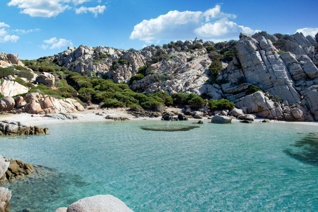 Traumstrand Cala Napoletana im Nationalpark des La Maddalena Archipels mit türkisblauem Wasser und Felsen im Hintergrund