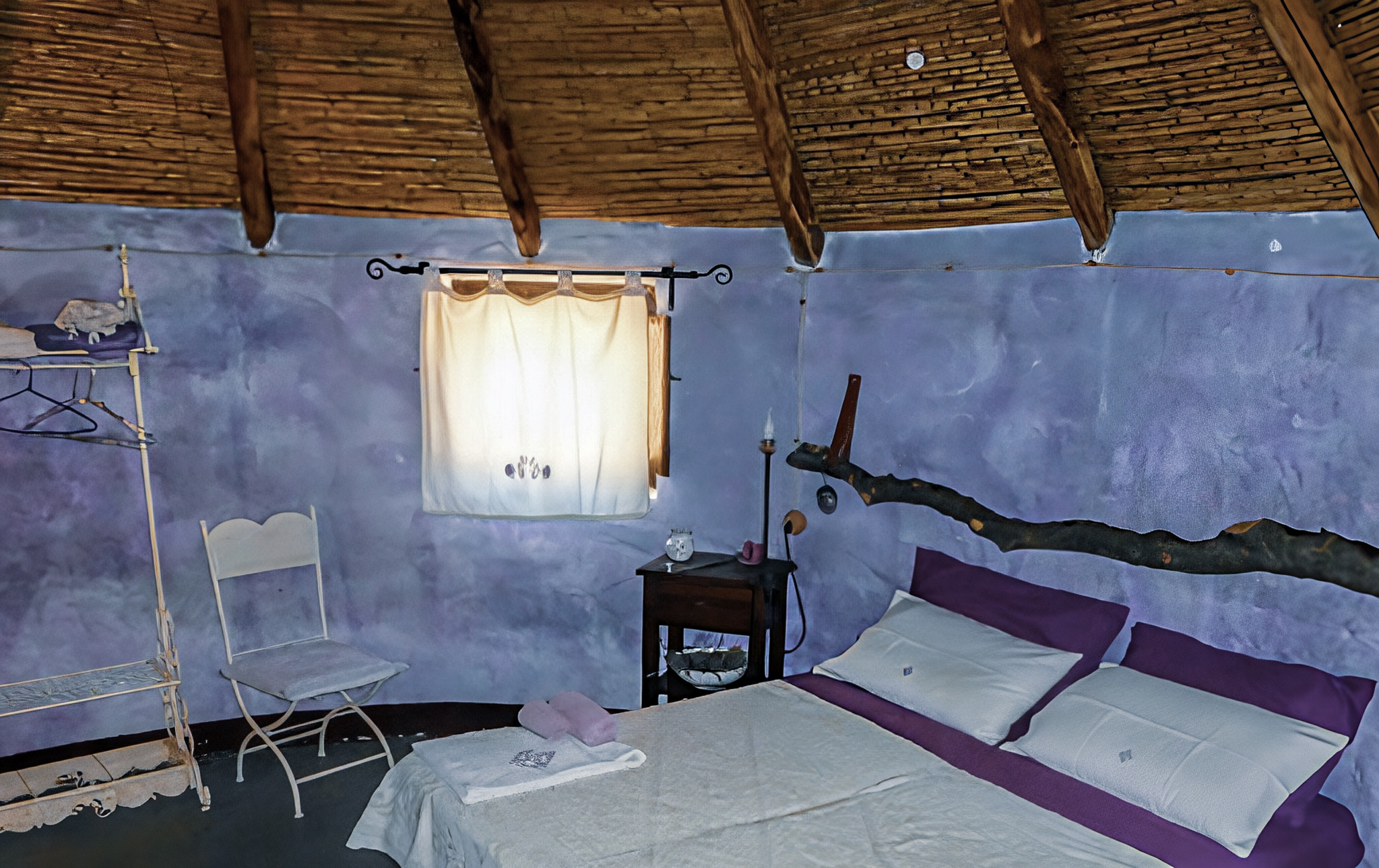 Blick in den Schlafraum mit Bett und Stuhl im Lavendel-Pinnettu von der Unterkunft L'Essenza