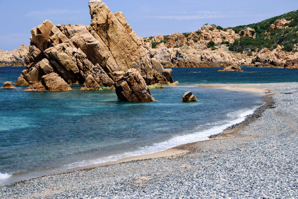 Li Tinnari mit Kiesstrand, rötlichen Felsen und türkisblauem Wasser