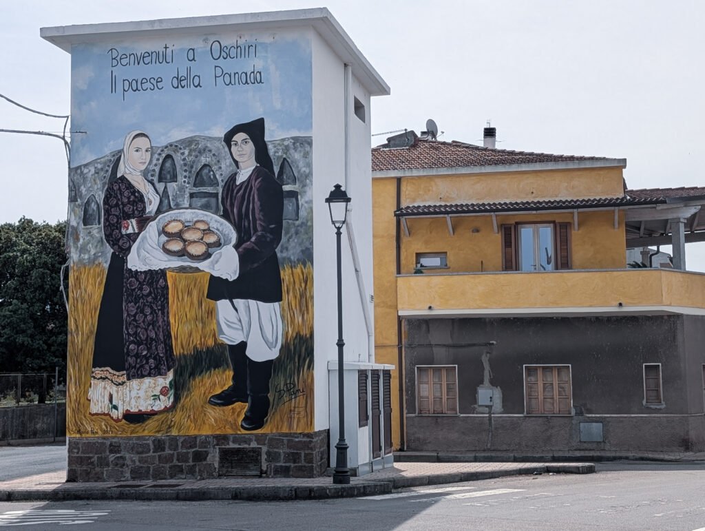 Wandbild in Oschiri mit traditioneller sardischer Kleidung und Panadas
