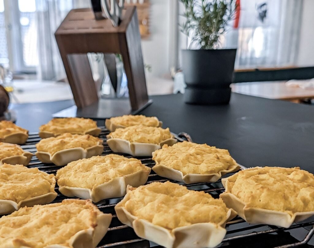 Selbst gebackene sardische Pardulas mit goldgelber Ricotta-Safran-Füllung auf einem Kuchengitter